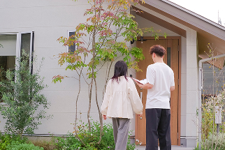 写真：モデルハウスの外でこれから内覧をしようとしている夫婦の後ろ姿
